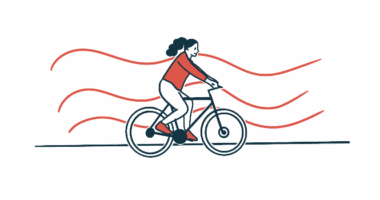 A person in a red shirt rides a bicycle in front of a background of wavy red stripes.